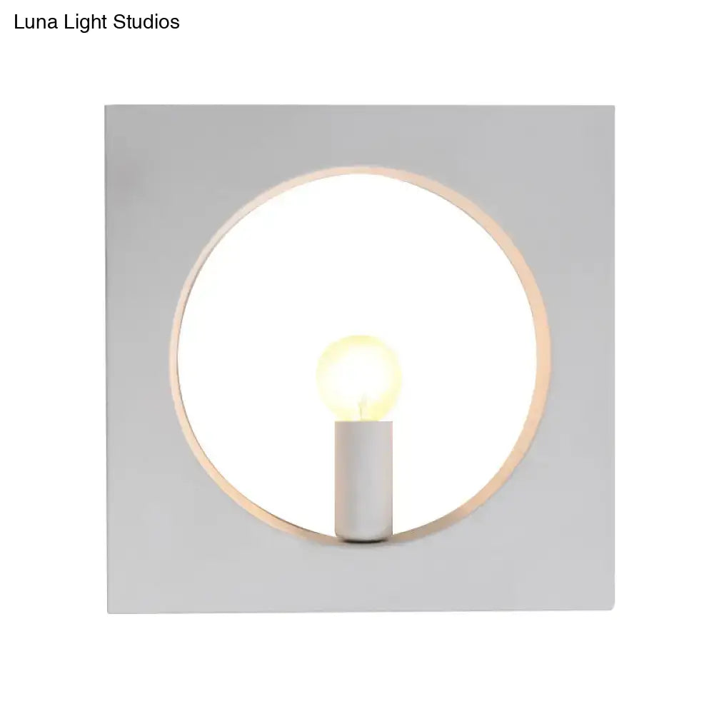 Minimalist wall lamp with circular wooden frame, white matte square backplate, and medium base candle bulb fixture