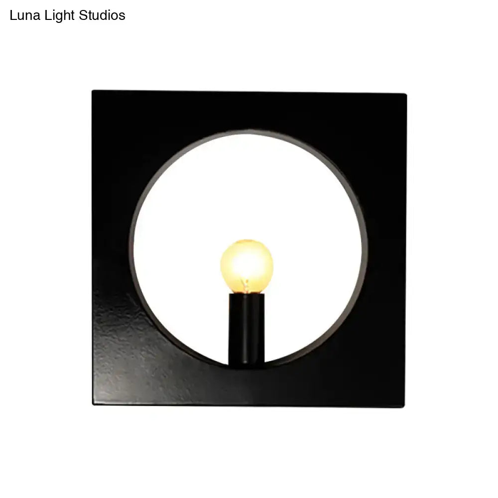 Modern black wall lamp with square glass fixture and circular cutout framing illuminated medium base bulb