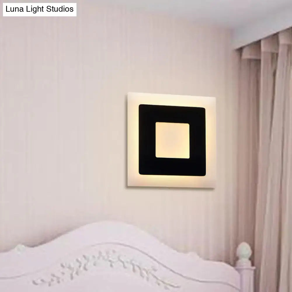 Modern black and white square wall sconce lamp with sleek frame and warm glowing center for bedroom lighting