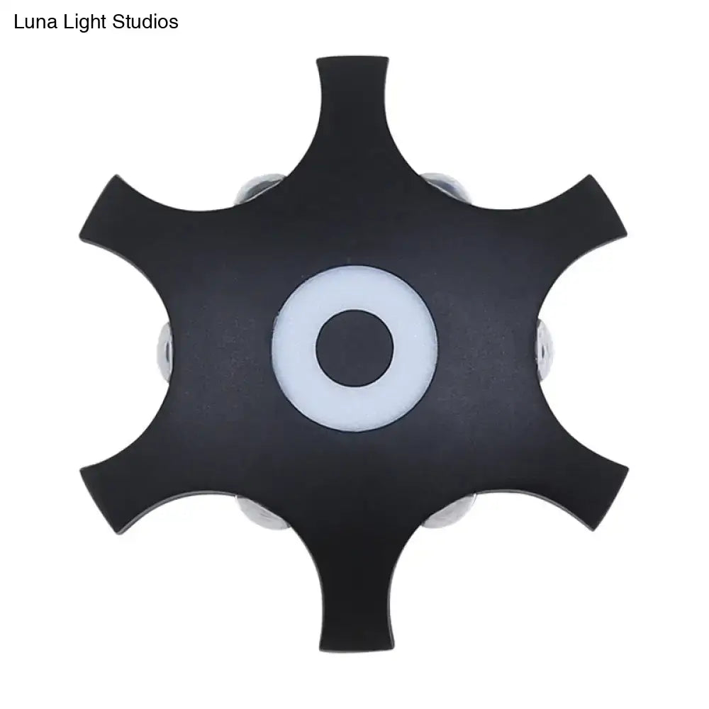Modern black star-shaped ceiling light fixture with white ring and silver bulb housings providing warm white light
