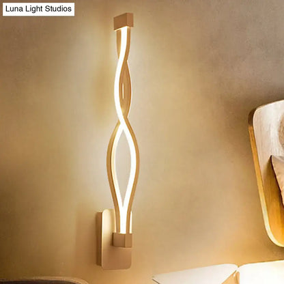 Modern gold-toned wall light sconce with a sleek twisted design providing warm ambient lighting for living rooms 110v-120v