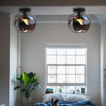 Industrial-style globe ceiling light shade with black metal cage and warm filament bulbs for living room use