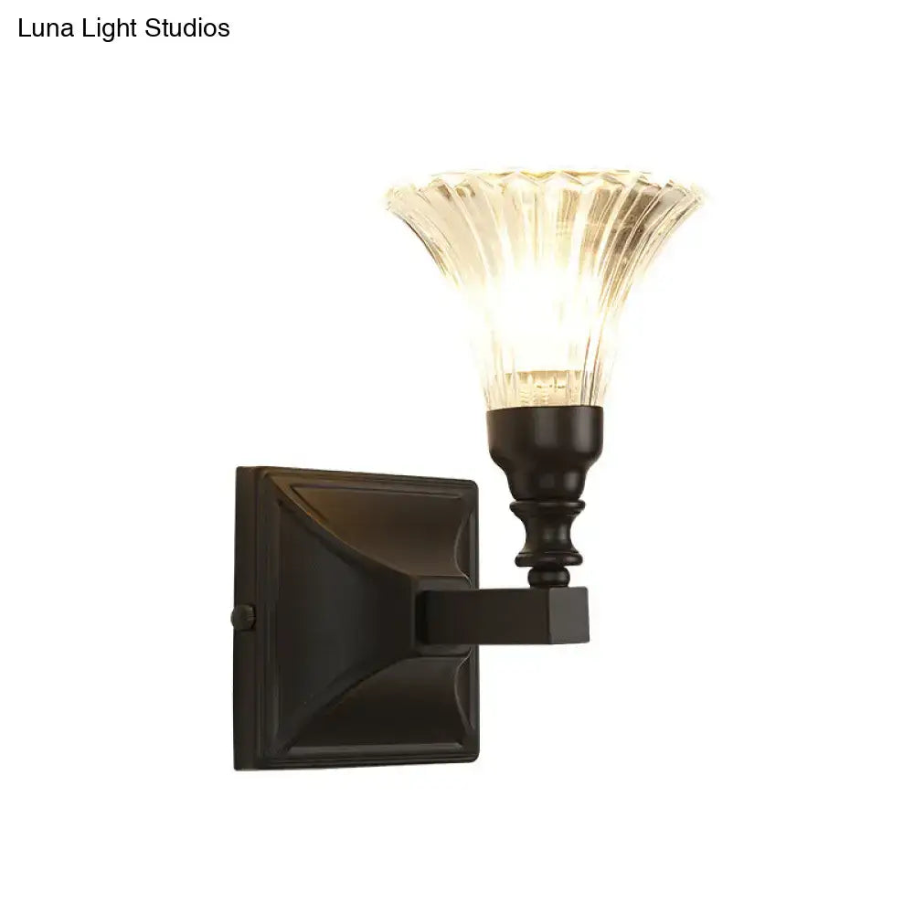 A modern black wide flare flush mount wall sconce with a dark bronze base and fluted translucent glass shade
