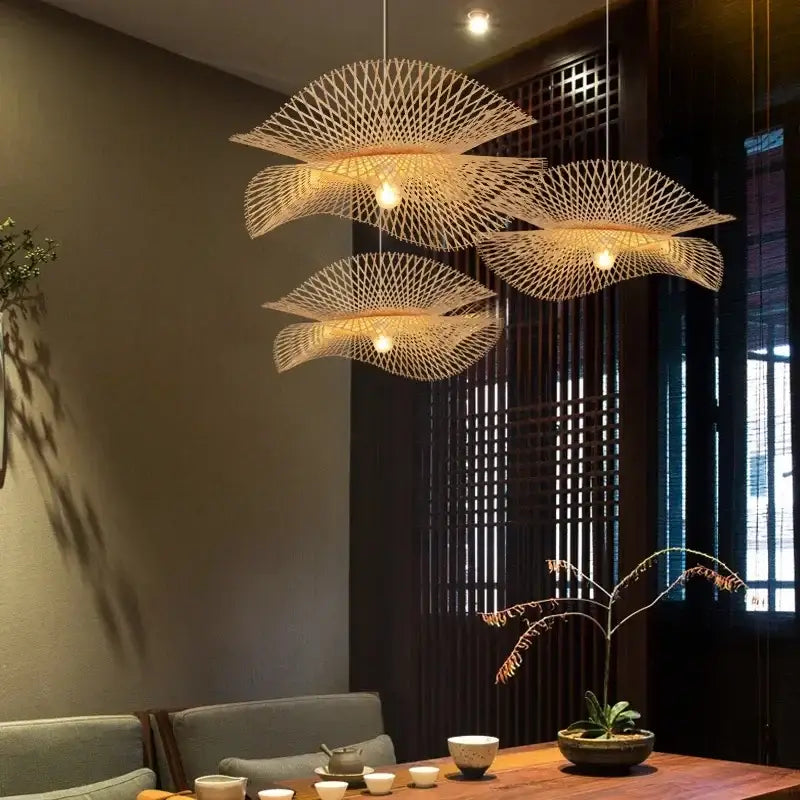 Three elegant light-brown woven bamboo pendant lights with fan-like design complement modern black woven metal pendant lights decorbites