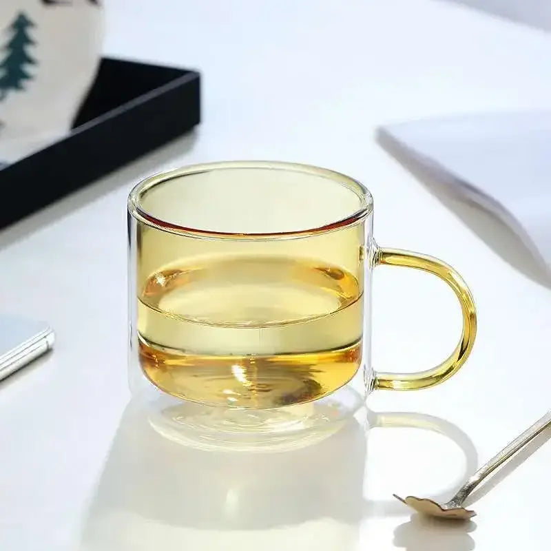 Clear double-walled glass mug with golden handle filled with amber liquid from modern blue amber and green glass mugs set