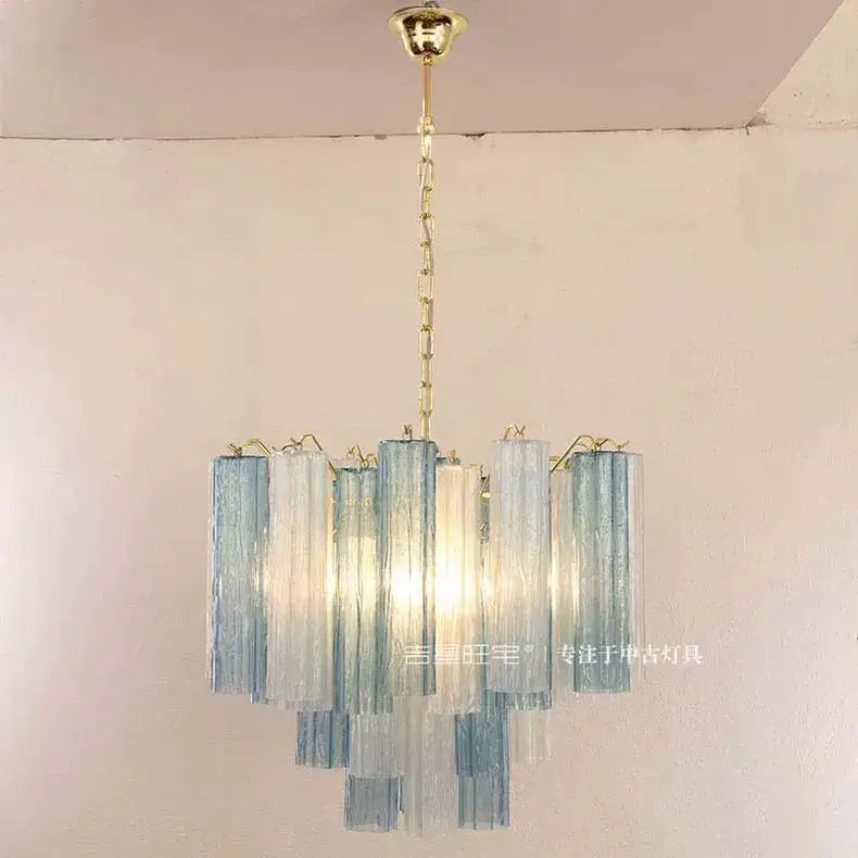 A modern blue and clear colorized glass led chandelier with cascading panels and brass chain for living room decorbites decor