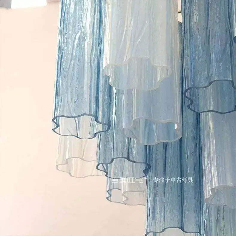 A translucent blue and white layered curtain with ruffled edges complements decorbites colorized glass led chandelier