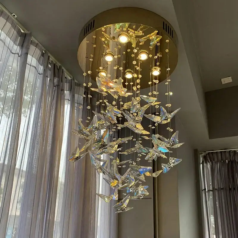 Modern blue and clear decorbites crystal staircase chandelier with golden circular frame and crystal butterfly accents