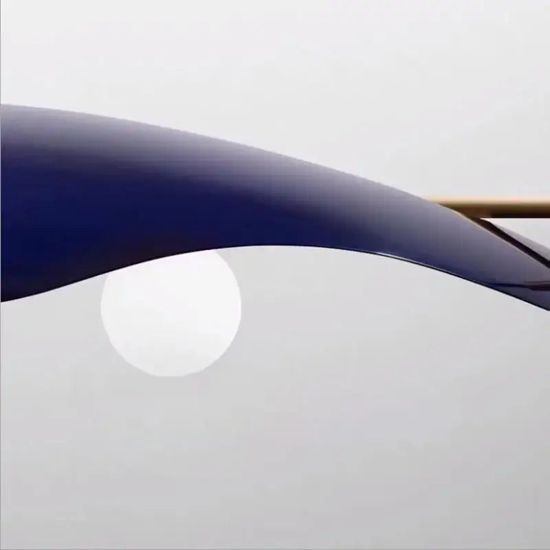 A sleek curved navy blue metal arm of a modern decorbites glass bubble chandelier dining room pendant light