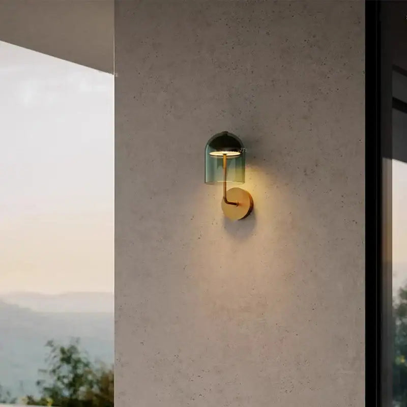 A modern wall lamp featuring a translucent green glass dome and brass arm from decorbites blue glass wall sconces
