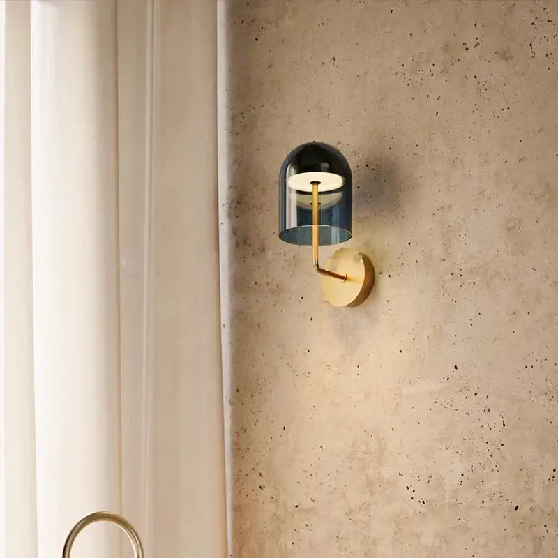 A sleek modern wall lamp with a blue glass dome and brass arm for decorbites blue glass wall lighting