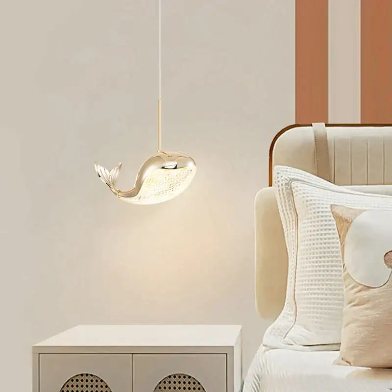 A sleek gold-toned whale-shaped pendant light with polished metallic finish in decorbites dolphin chandelier style