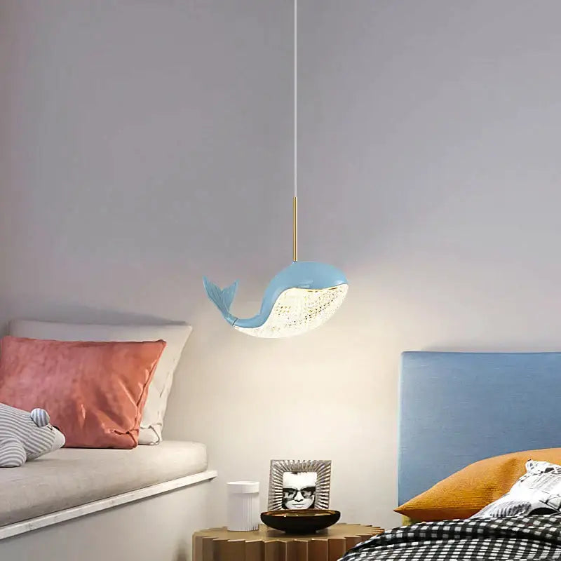 A light blue whale-shaped decorbites dolphin chandelier with white textured underside and gold-toned hanging rod