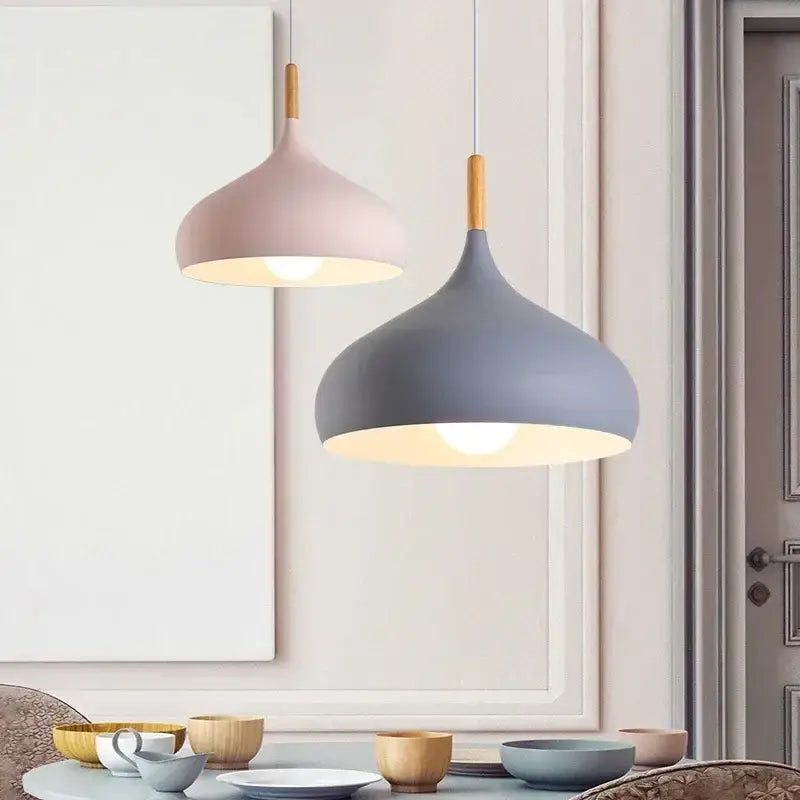 Two modern pendant lights with matte pink and gray finishes stainless steel construction wooden stems and warm glow