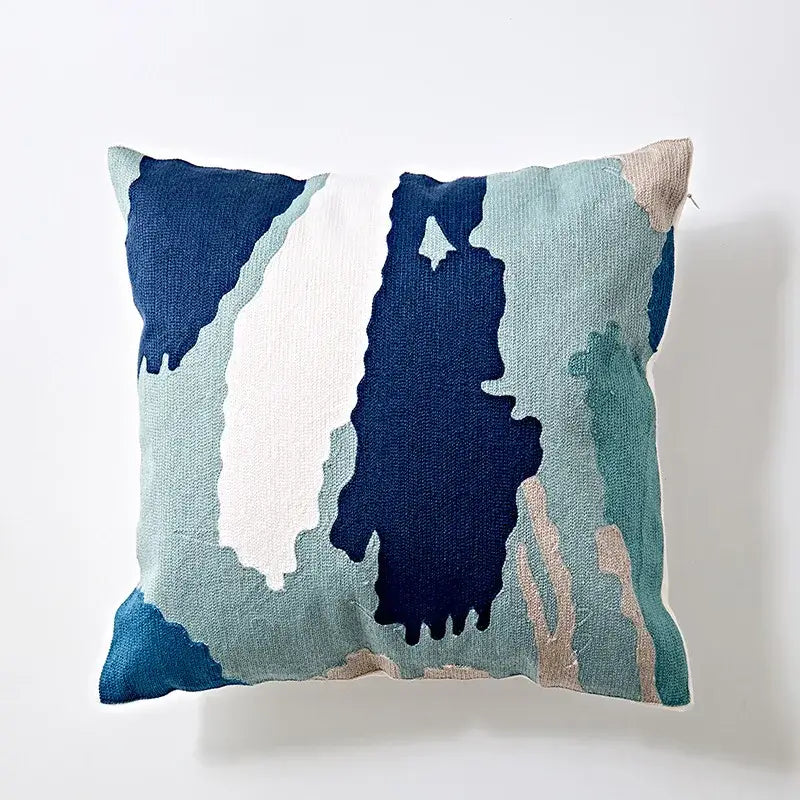 A modern blue and white embroidered geometric cotton cushion cover with abstract navy teal and beige design for bedroom