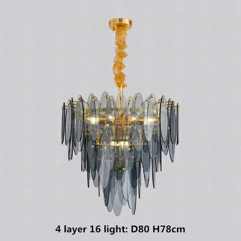 A modern pendant light with four tiers of translucent gray glass leaves on a decorbites gold metal chain