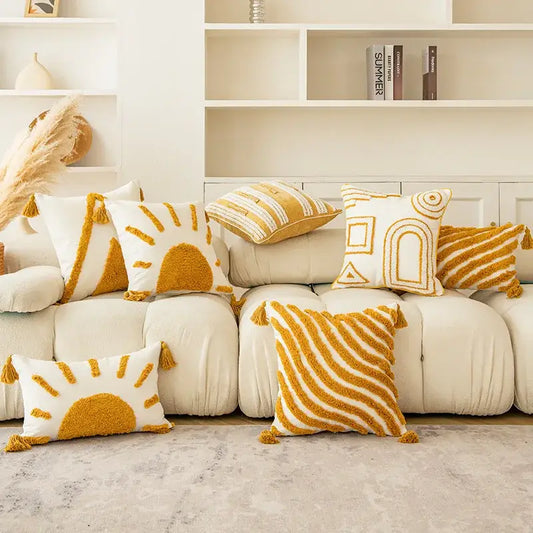 A modern boho mustard yellow and cream cushion cover with tassel accents featuring golden yellow geometric and sun motifs