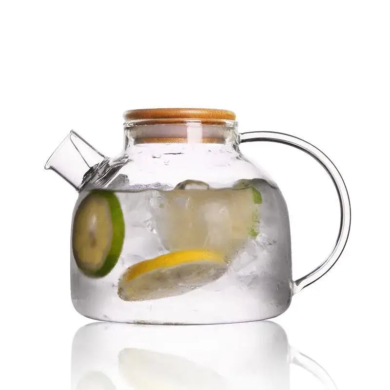 Modern borosilicate glass teapot with bamboo lid and wood handle containing ice and lemon lime slices for kitchen use