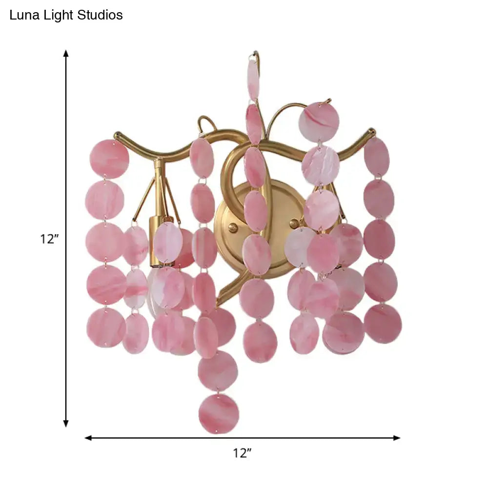 A delicate pink branch design wall lamp with a gold frame and oval rose quartz slices for bedroom sconce use