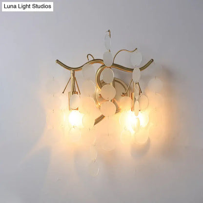 Gold-toned wall lamp with branch design featuring curved metal arms and translucent white discs for bedroom sconce decor