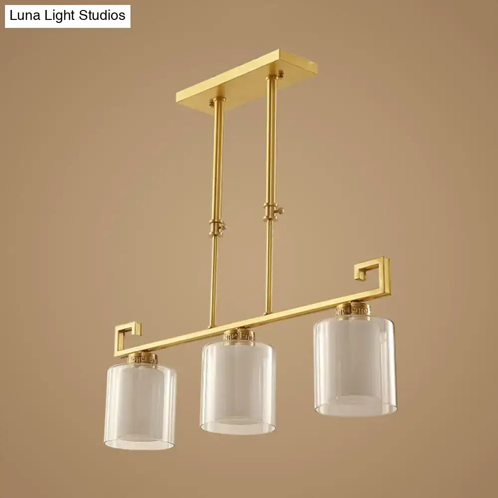 Gold-toned decorbites™ classic cylinder island lighting with three clear glass pendulum lamps and brass finish frame