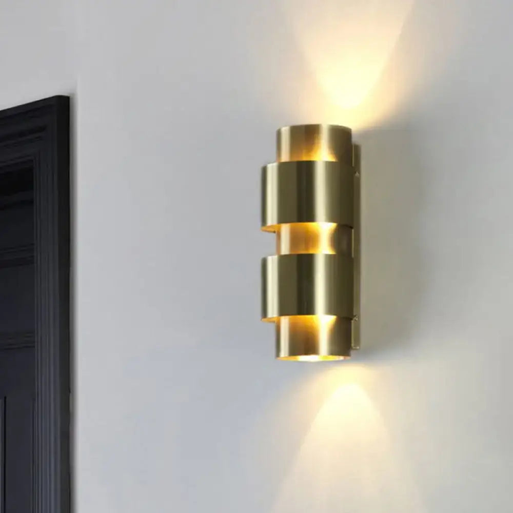 Modern brass 3 tier metal shade wall sconce with stacked cylindrical tiers emitting warm focused light for foyer use