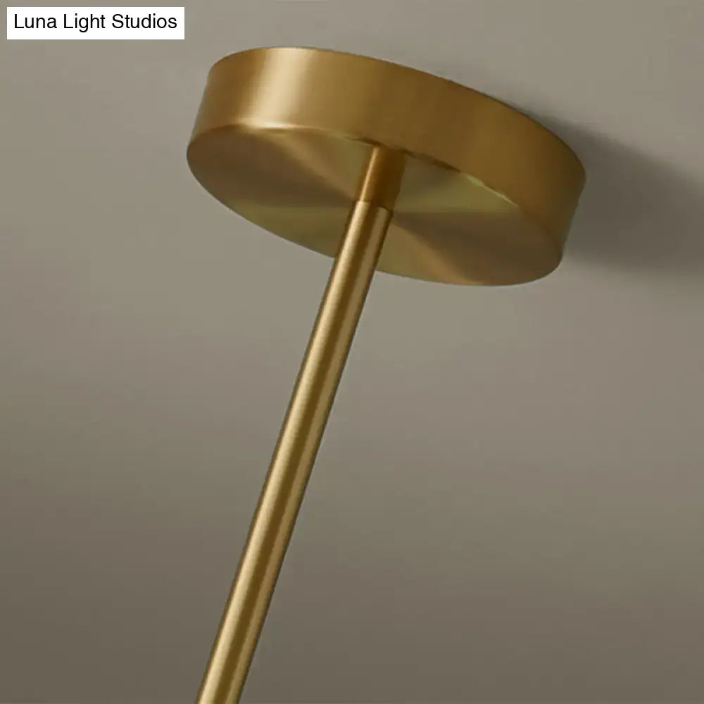 Modern brass pendant light with a brass-finished cylindrical stem and circular mounting plate featuring spherical glass shade