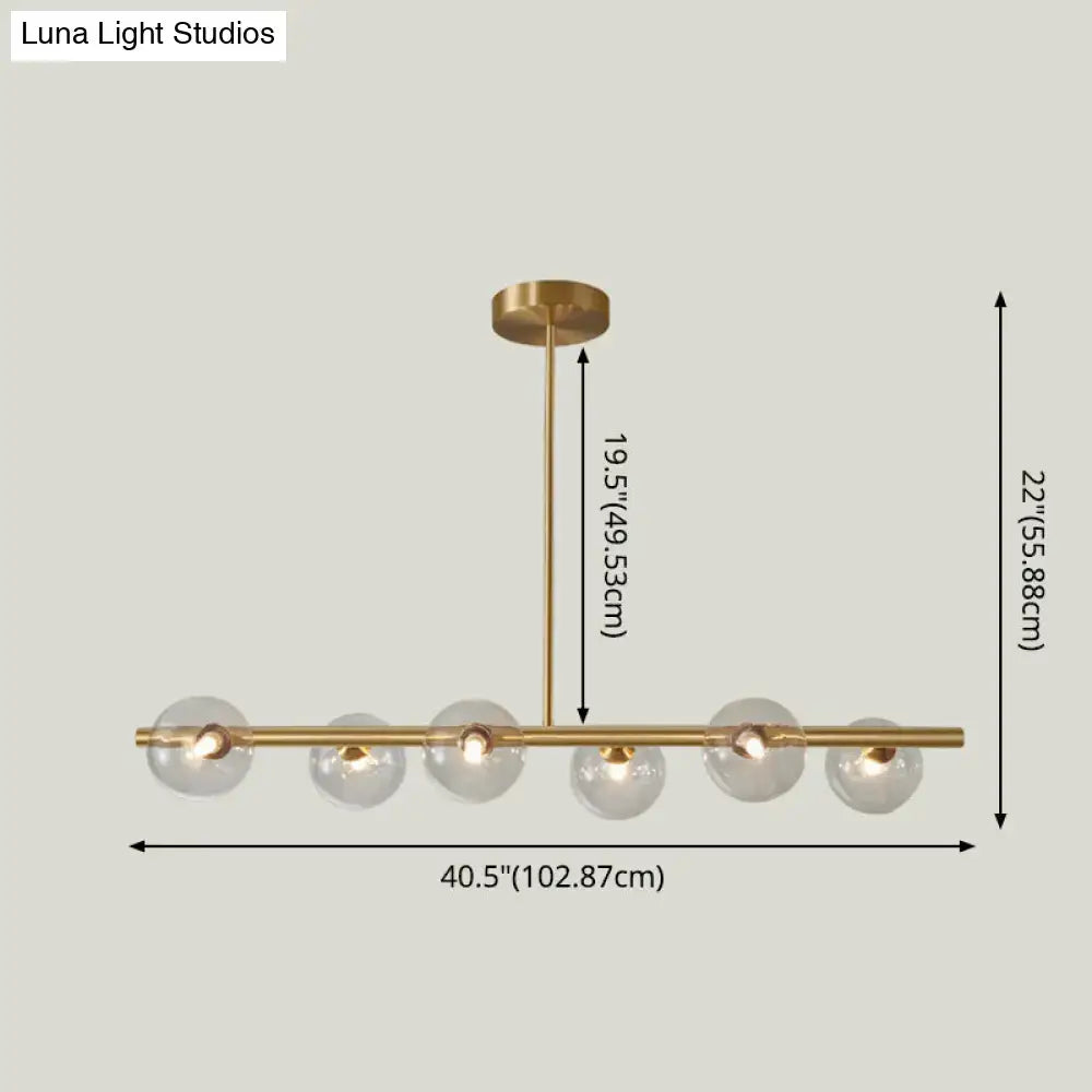 Modern brass pendant light with five clear spherical glass shades for dining room illumination