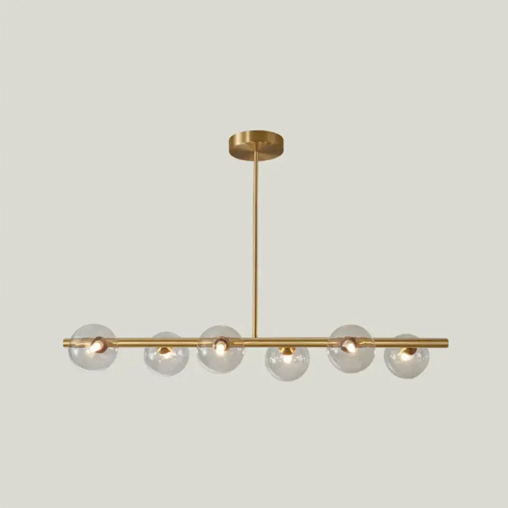 Modern brass pendant light with six clear spherical glass shade bulbs in a linear design for dining room use