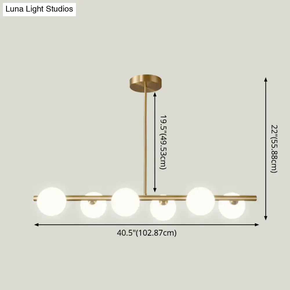 Modern brass 5-light pendant light with spherical glass shade featuring five frosted globe bulbs in a linear design