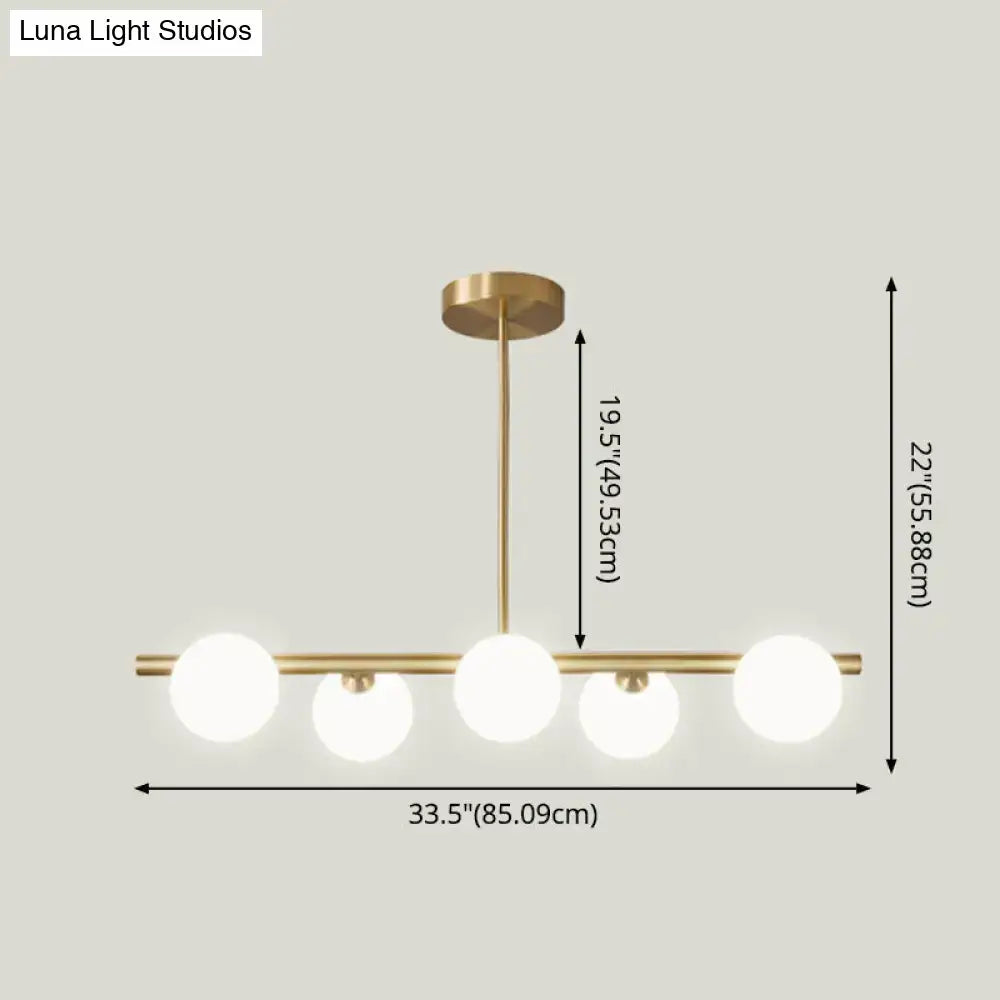 Modern brass 5-light pendant light with spherical glass shade featuring four frosted glass globes in a linear design