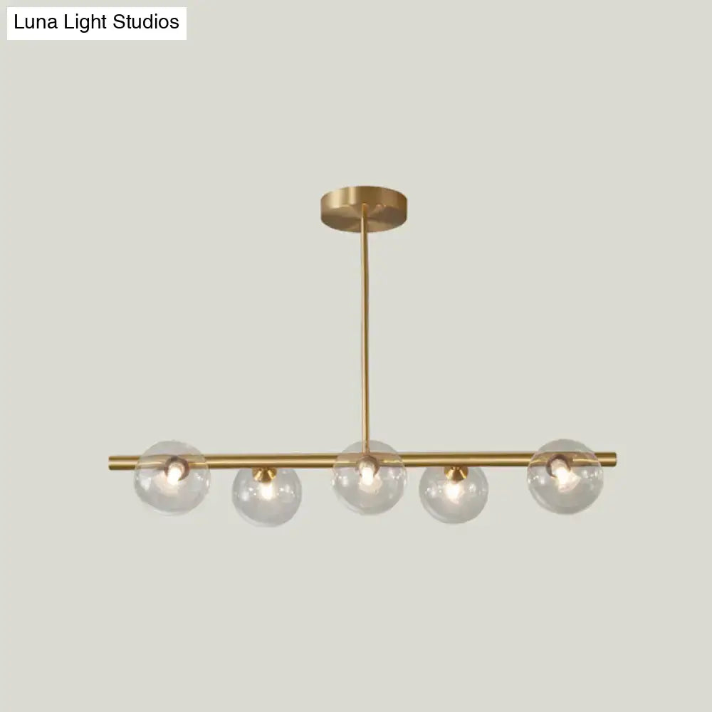 Modern brass 5-light pendant light with spherical glass shade featuring five clear glass globes on a horizontal bar