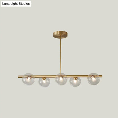 Modern brass 5-light pendant light with spherical glass shade featuring five clear glass globes on a horizontal bar