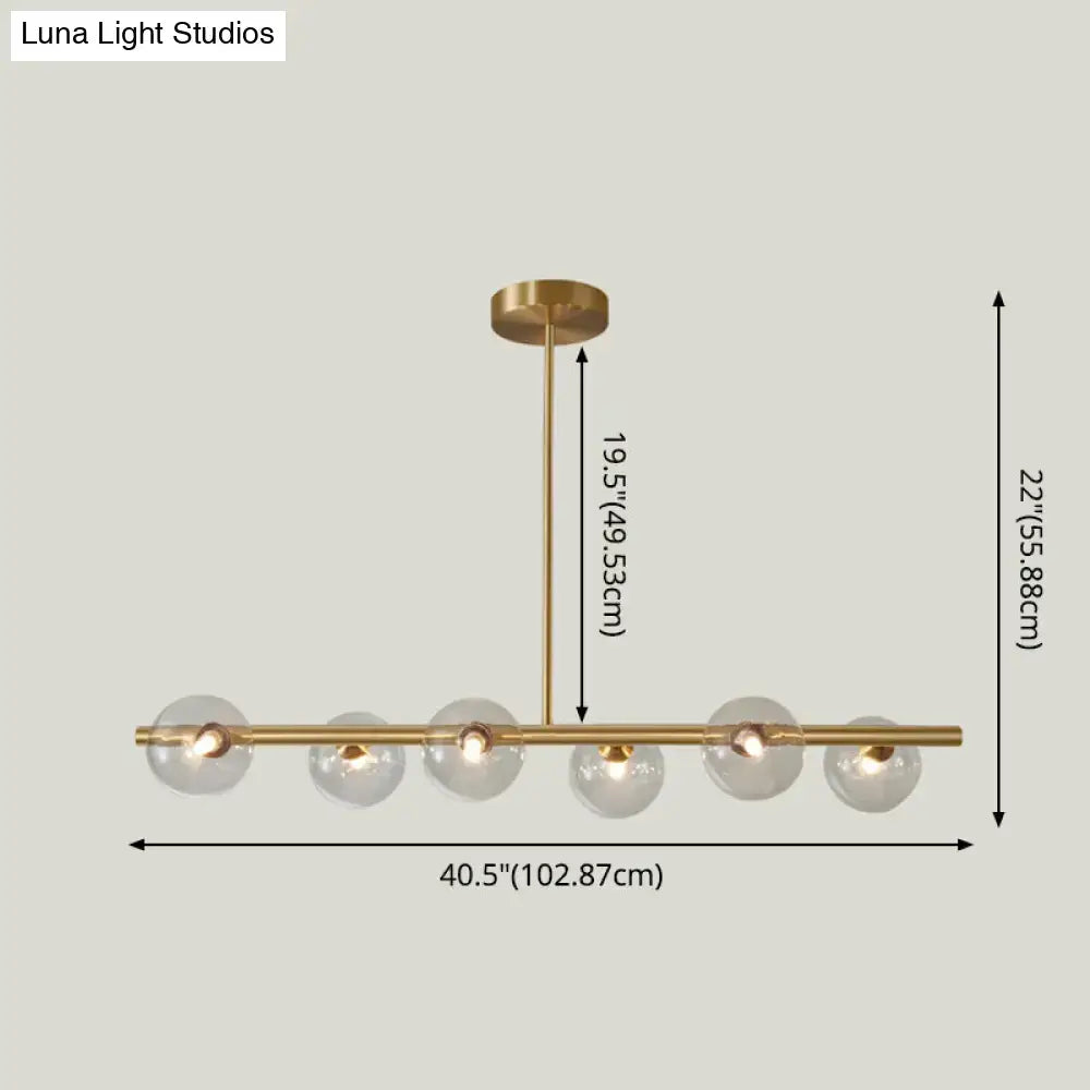Modern brass 5-light pendant light with spherical glass shades featuring clear glass globes for dining room use