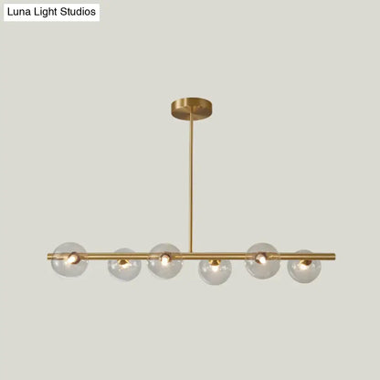 Modern brass pendant light with six gold-toned spherical glass shades on a horizontal bar for dining room lighting