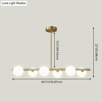 Modern brass 5-light pendant light with spherical glass shade featuring five frosted glass globes in a linear design