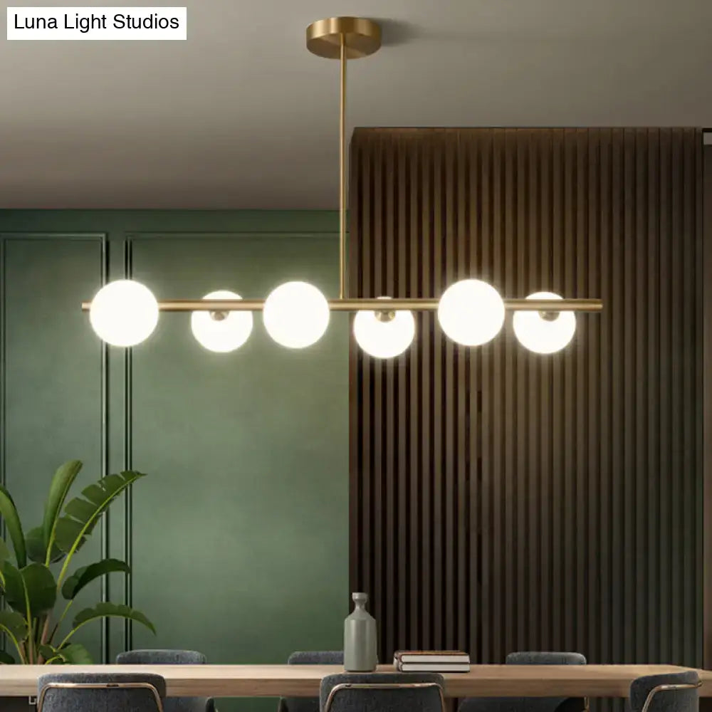 Modern brass pendant light with five frosted spherical glass shades designed for dining room illumination