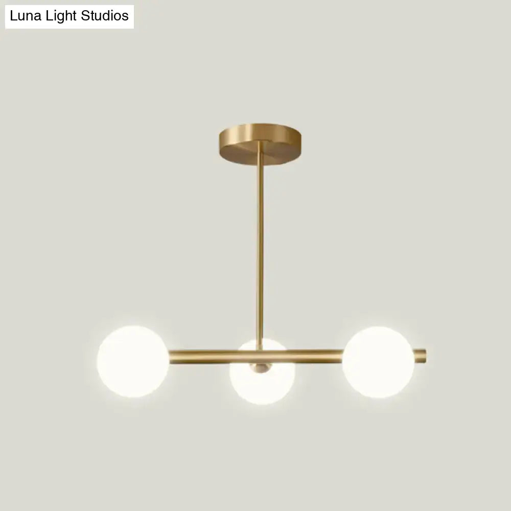Modern brass pendant light with three spherical frosted glass bulbs featuring spherical glass shades for dining room