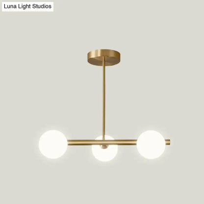 Modern brass pendant light with three spherical frosted glass bulbs featuring spherical glass shades for dining room