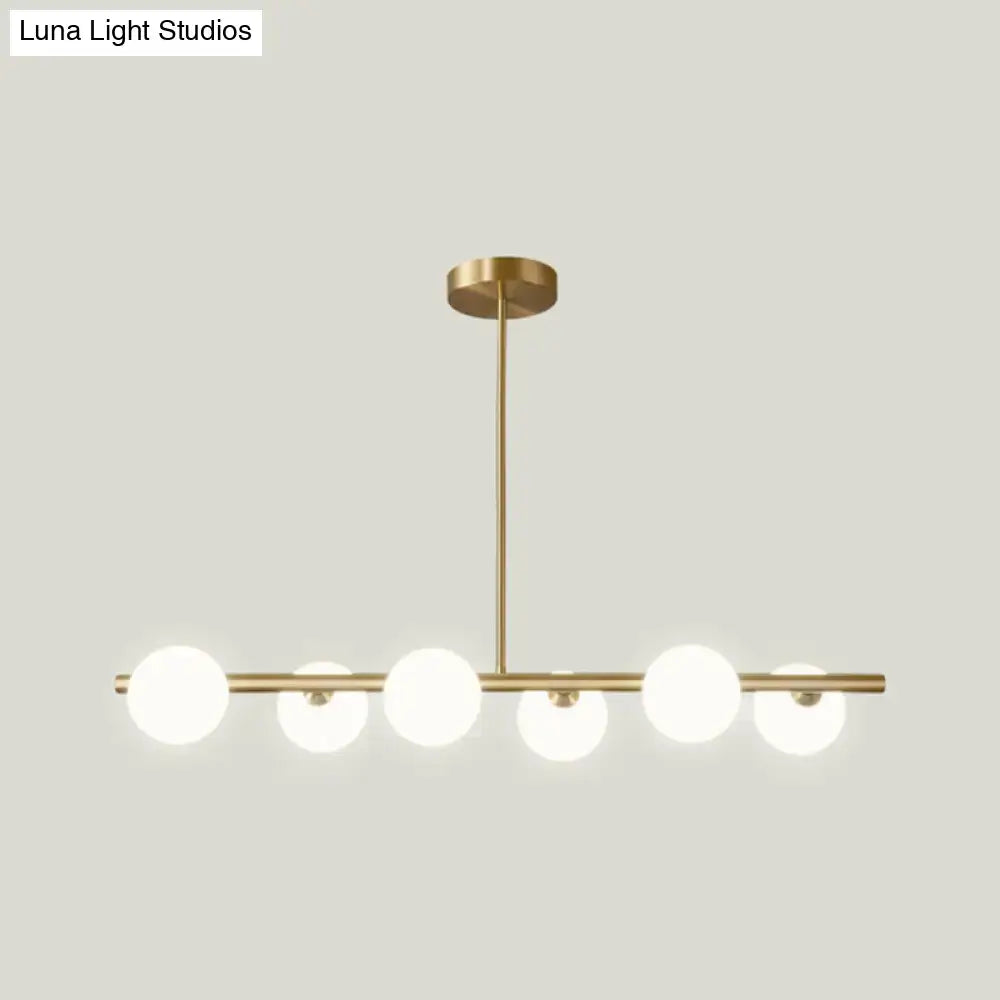 Modern brass 5-light pendant light with spherical glass shade featuring frosted globes in a dining room setting
