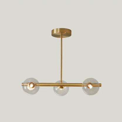 Modern brass pendant light with five spherical glass shades and gold-toned minimalist metal arms for dining room