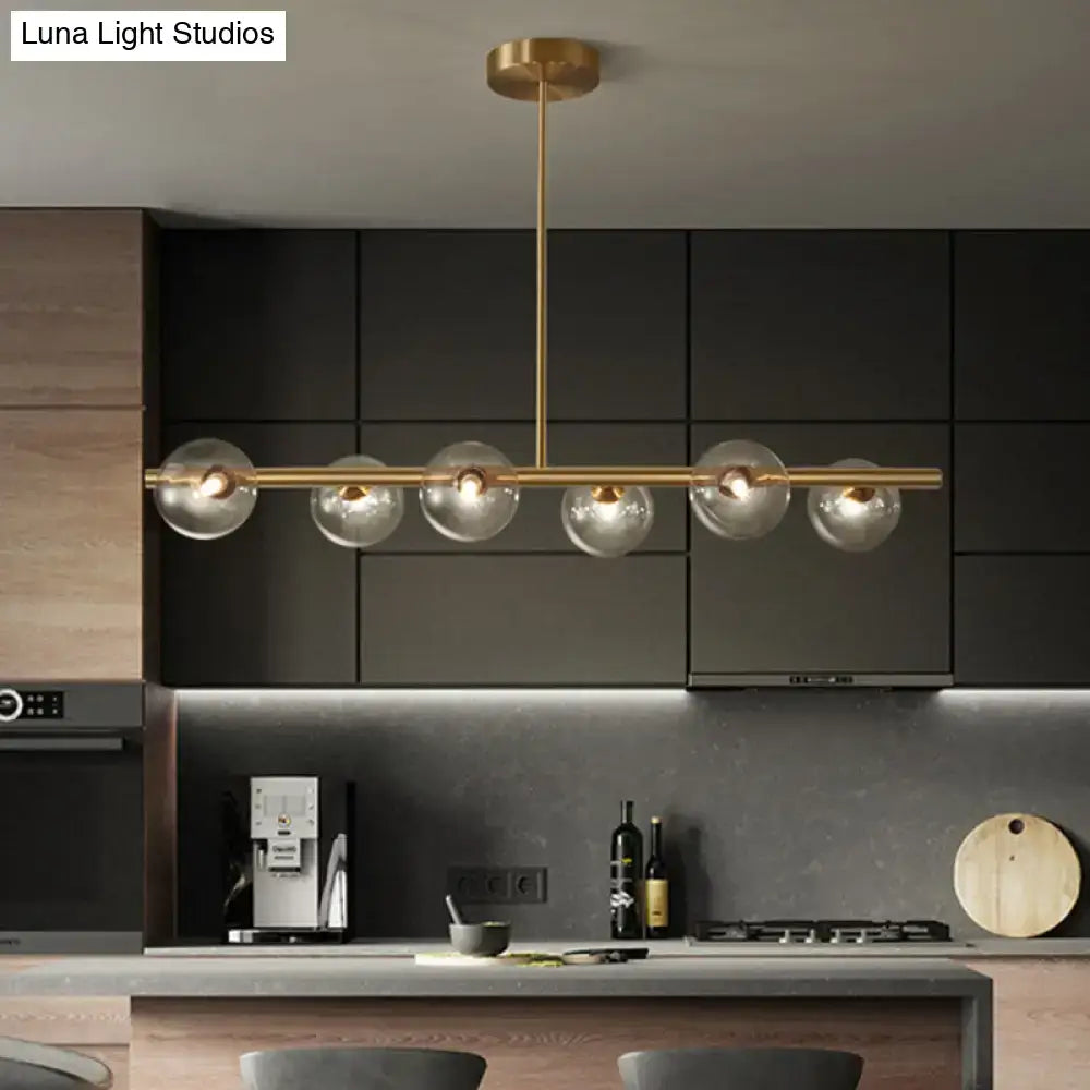 Modern brass pendant light with five spherical glass shades designed for dining room illumination