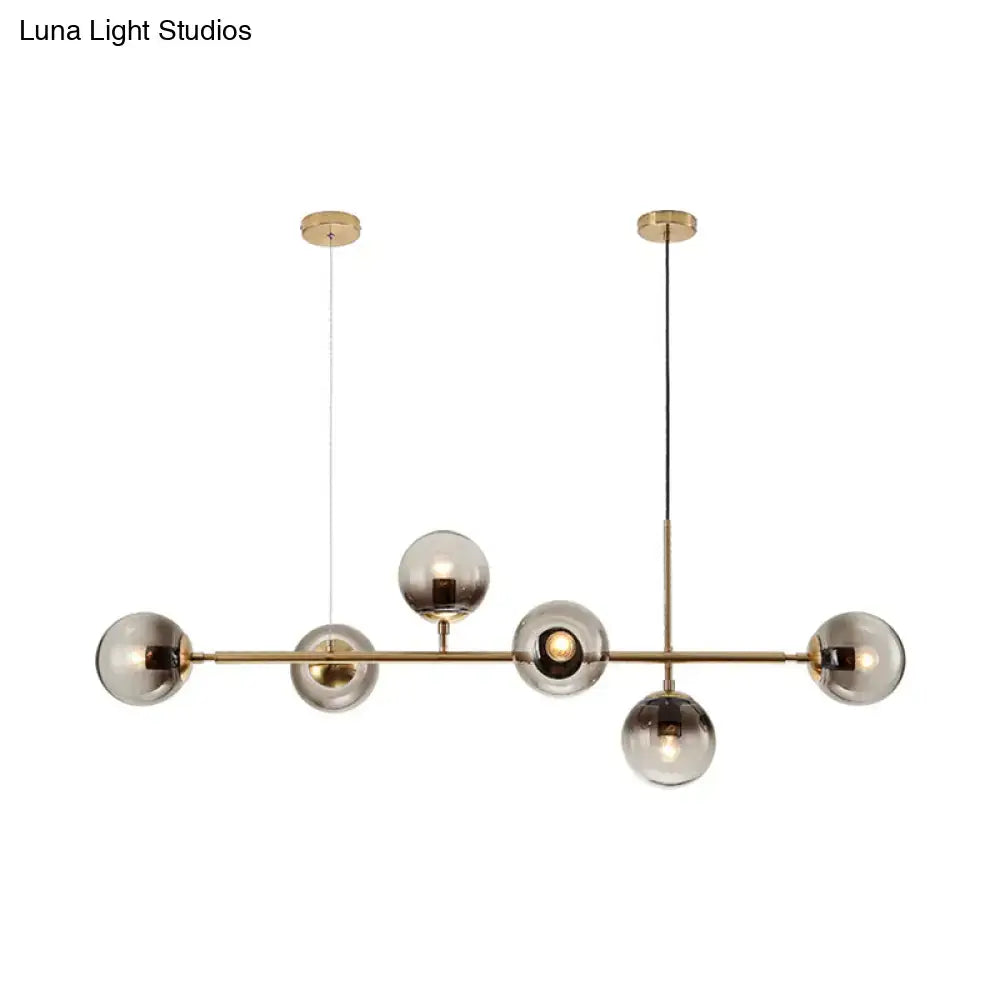 Modern brass six light chandelier with smoke gray glass shades featuring a sleek minimalist design for dining room lighting