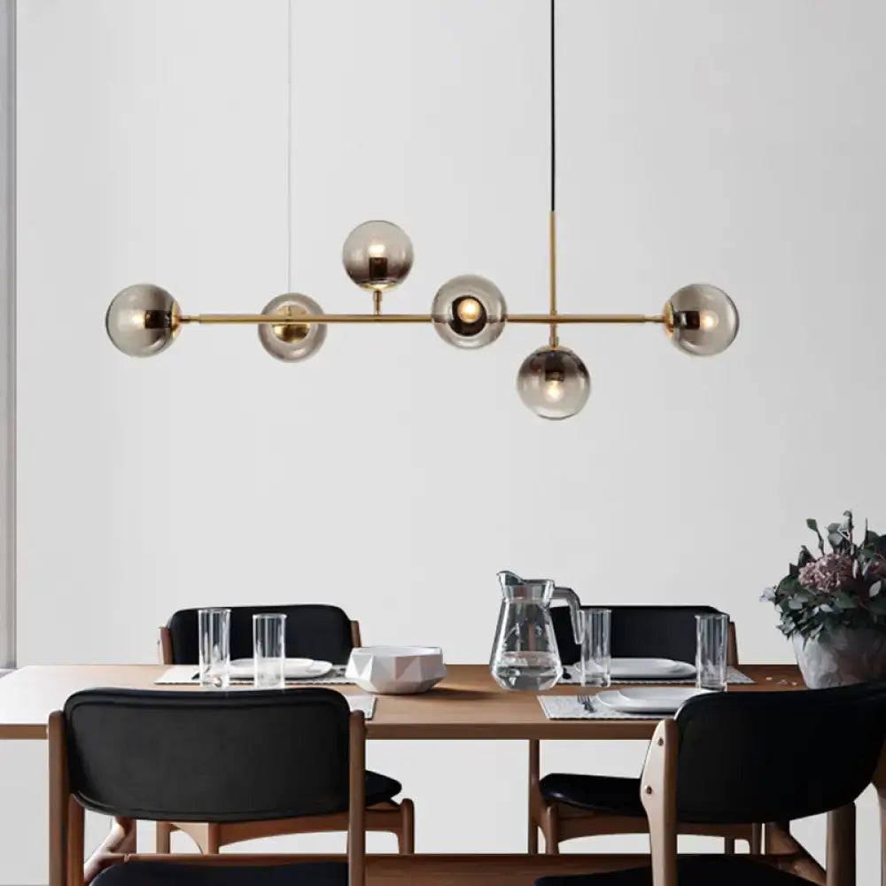 Modern brass 6 light dining room pendant with smoke gray glass shades and six smoked glass globe bulbs in a linear design