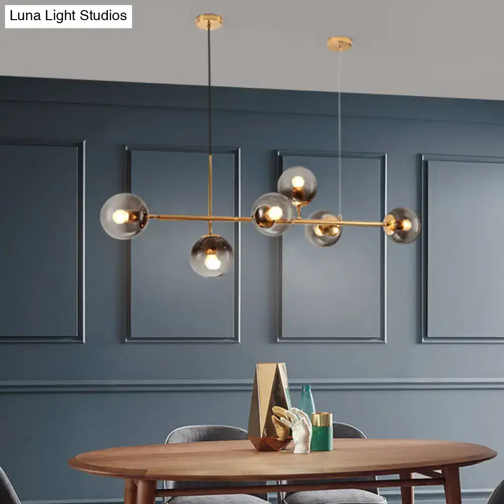 Modern brass 6 light dining room chandelier with gold-toned frame and smoke gray glass shades in spherical globes