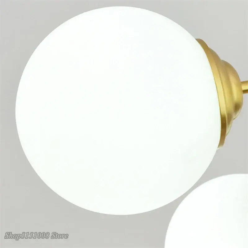 Modern brass 8-light glass ball pendant lights featuring white frosted glass globe and brass-finished metal fixture