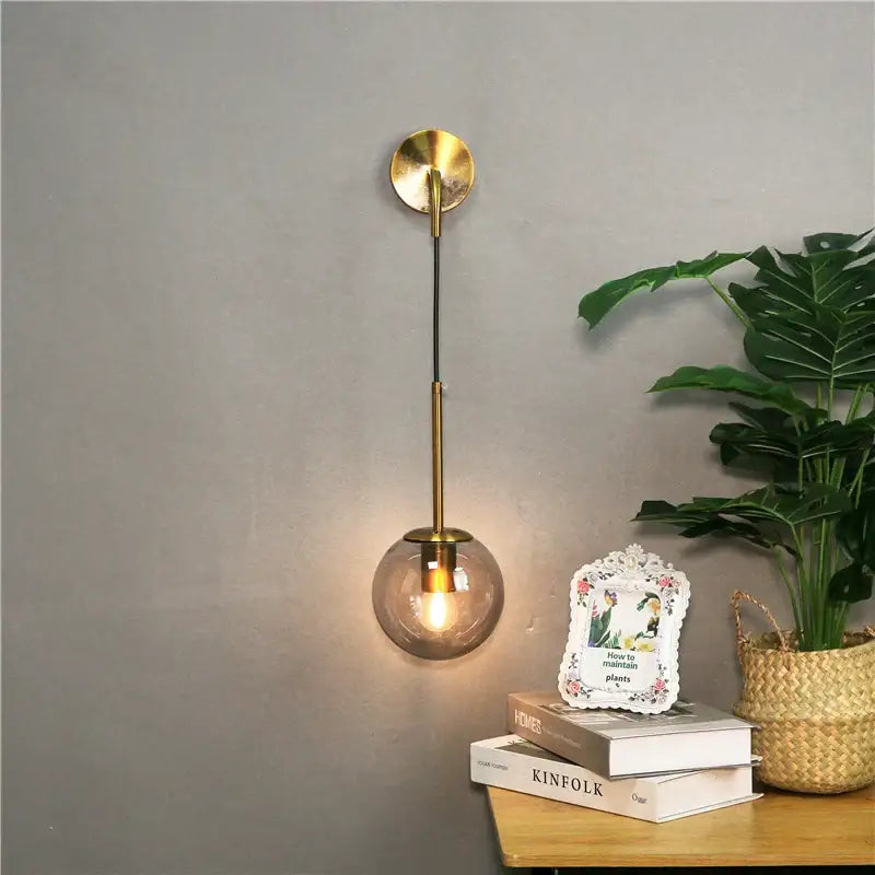 Modern brass wall lamp with a spherical smoked amber glass ball shade for bedroom decorbites glass ball wall lighting