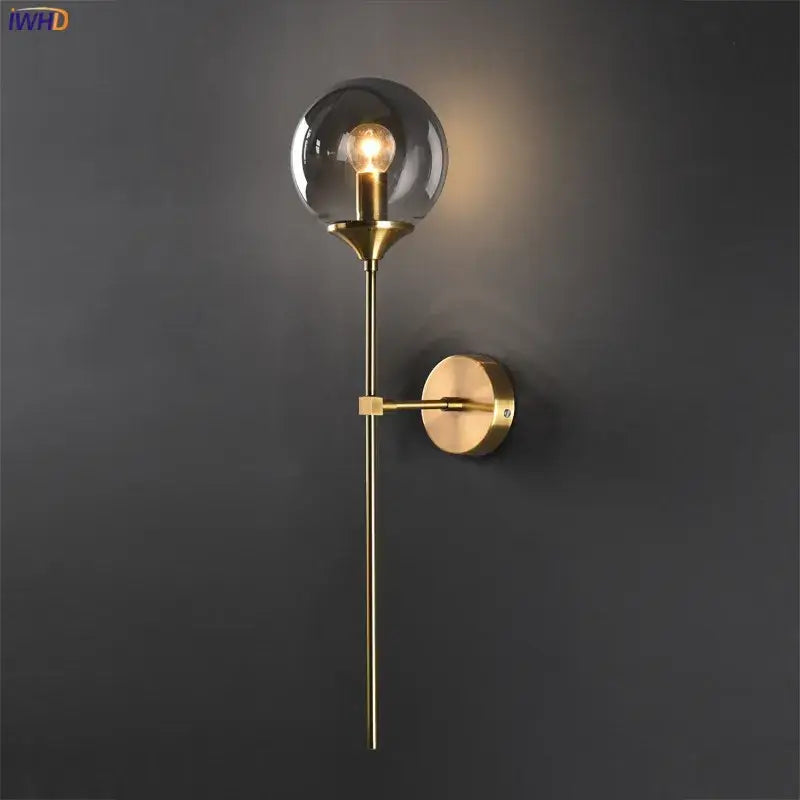 Modern brass and amber decorbites glass ball wall lamp with gold-toned stem and spherical smoked glass shade for bedroom
