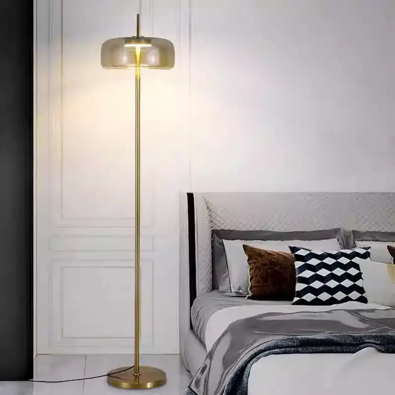 Modern brass and amber glass led floor lamp with gold finish and cylindrical glass shade for living room lighting