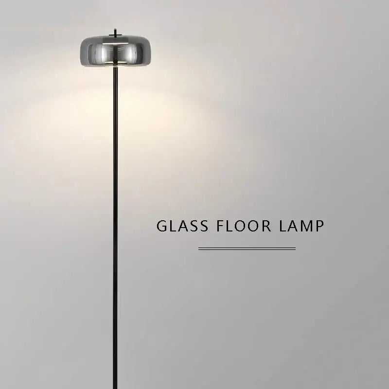 Modern brass and amber glass led floor lamp with sleek cylindrical chrome shade and black metal stand for living room lighting